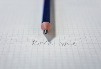 Words LOVE ME on paper and pencil