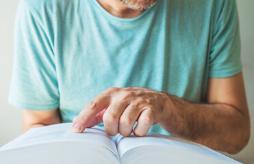 Closeup of man searching for the term in the dictionary, finger pointing to a book page