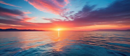 Fototapeta premium Vibrant sunset over the sea with a beautiful array of colors reflecting off the rippling water creating a stunning vista with a copy space image