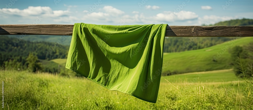 Wall mural cloth left on a fence with copy space image of green grass in the background