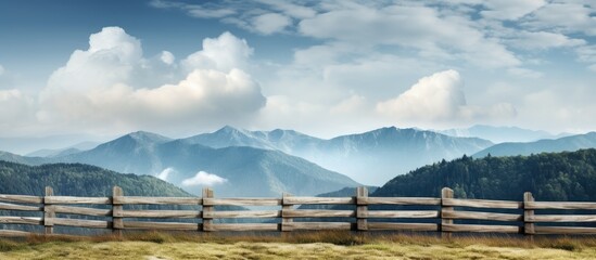 Fototapeta premium A fence along a mountain with cloudy skies in the background offering a serene view with copy space image