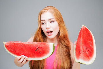 Surprised and funny young beautiful woman eating watermelon isolated on gray background. Healthy...