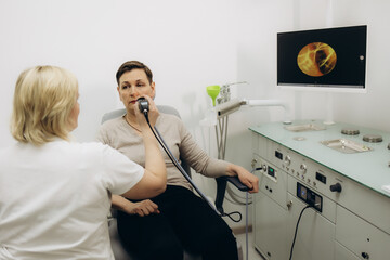 Nose endoscopy. Rhinoscopy procedure with rhinoscope. ENT doctor otolaryngologist with headlight treat nose woman patient