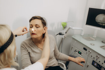 Rhinoscopy of woman nose. Consultation with ENT doctor. Otolaryngologist examines girl nose before...