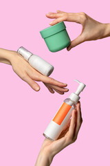 Woman`s hands showing set of cream products. Cosmetic product branding mockup. Daily skincare and body care routine. Female hand holding  cosmetic product mockup on a light pink background. Close up.