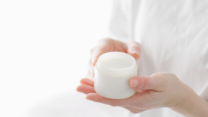 スキンケアクリームを手に塗る女性