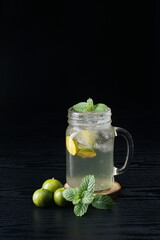 orange juice with mint leaves in a mug on a black table with studio lighting, In Indonesia this drink is called 