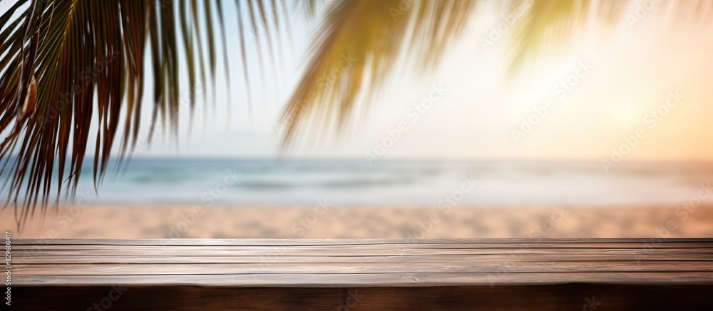 Poster wooden table with no items on it and palm leaves are displayed against a blurred beach party backgro