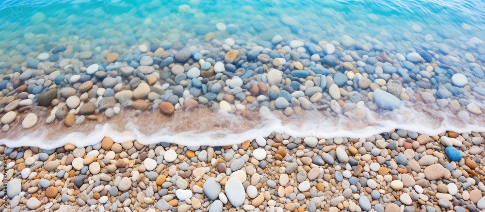 Aufkleber sandy beach with colorful pebbles crystal clear waves gently foaming under the sun on a summer day w