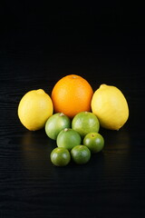 sunkist oranges, lemons, and limes on a black table with a black background with studio lighting