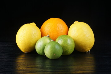 sunkist oranges, lemons, and limes on a black table with a black background with studio lighting