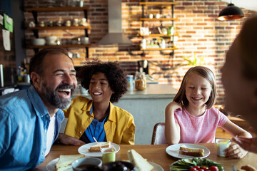 Multiracial family laughing together at breakfast table