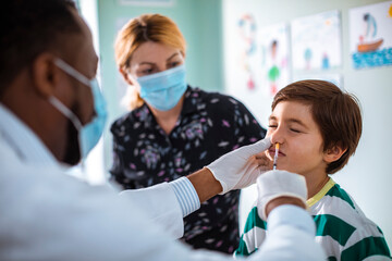 Pediatrician administering nasal vaccine to a young boy