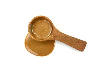 Sesame sauce in a wooden spoon isolated. Tahini isolated on white background