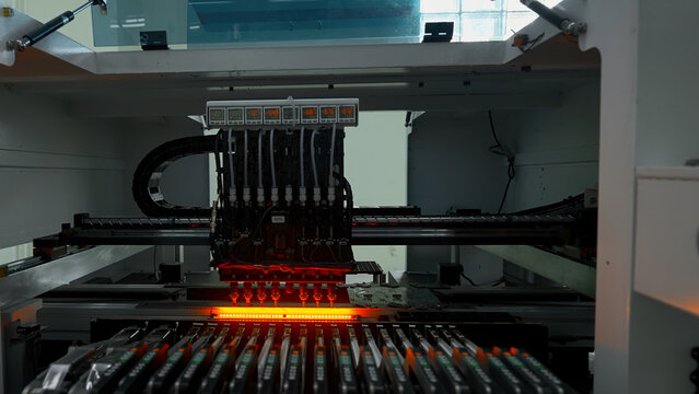 Automatic pick and place machine is installing components on circuit board. Creative. Assembly line on electronics and circuit board manufacturing factory.