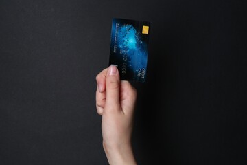 Woman holding credit card on black background, closeup