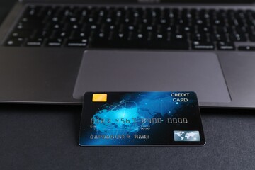 Credit card and laptop on grey table, closeup