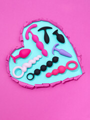 heart shaped hole in pink paper with adult toys for sex games inside
