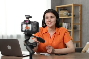 Smiling technology blogger with smartphones recording video review at home