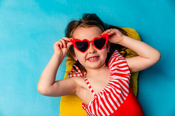 Top view little child girl in red swimsuit, resting on inflatable mattress for swimming, hotel...