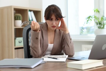 Overwhelmed office worker sitting at table with laptop indoors