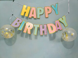 Colorful banner spelling out Happy Birthday on the wall. Happy birthday text with balloons.