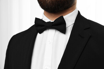 Man in suit, shirt and bow tie indoors, closeup