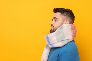 Handsome man in warm scarf on yellow background. Space for text