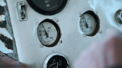 Switches and gauges inside the cabin of an old ship. Clip. Close up of blurred captain hand on wheel and dash board.