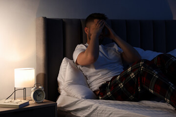 Man covering face with hands on bed. Insomnia problem