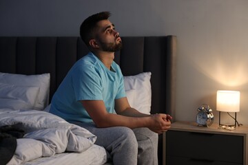 Man suffering from insomnia on bed at home