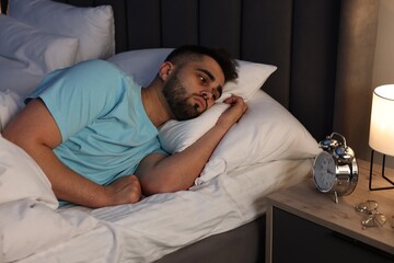 Frustrated man suffering from insomnia in bed