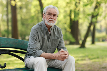 Obraz premium Portrait of happy grandpa with glasses on bench in park