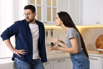 Annoyed wife screaming at her husband in kitchen. Relationship problems