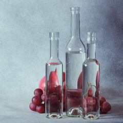 Still Life of Grapes Seen Through Water in Clear Glass Bottles