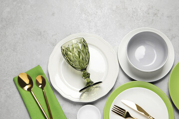 Beautiful ceramic dishware, glass and cutlery on light grey table, flat lay