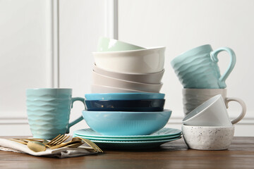 Beautiful ceramic dishware, cups and cutlery on wooden table