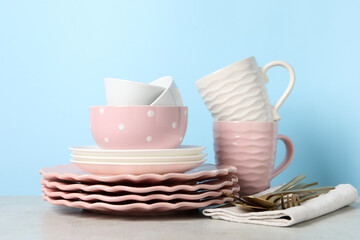 Beautiful ceramic dishware, cups and cutlery on light grey table
