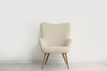 Comfortable armchair near white wall in room