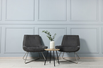 Comfortable armchairs, side table and eucalyptus indoors