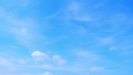 Naklejka premium A bright blue sky with a few scattered, fluffy white clouds. The sky appears clear and vast, suggesting a beautiful and serene day. The soft, light clouds add a gentle texture to the expanse of blue. 