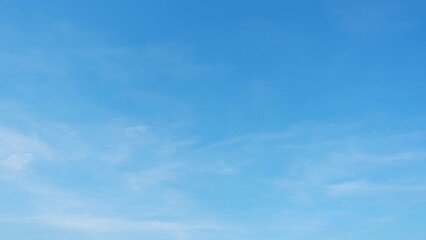 A clear blue sky with a few faint, wispy clouds. The sky is bright and expansive, suggesting a calm...