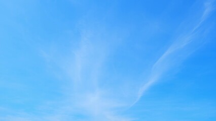 A clear blue sky with a few wispy clouds. The sky is bright and serene, indicating a sunny day with minimal cloud coverage, giving a sense of openness and calm. Horizon background.
