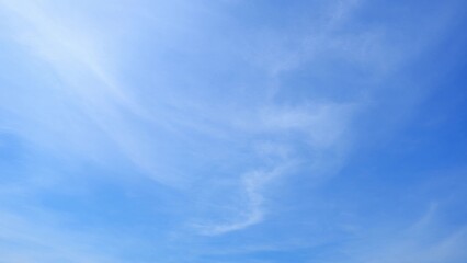 A serene blue sky with a few soft, wispy clouds dispersed throughout. The gentle clouds add a sense...