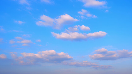 A bright blue sky adorned with scattered white clouds. The clouds vary in size and shape, creating a beautiful contrast against the vivid blue background, offering a sense of calm and serenity.
