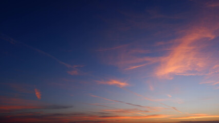 A stunning sunrise with a deep blue sky transitioning into warm hues of pink and orange. Wispy...