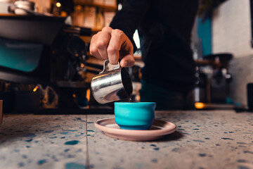 Close up of male barista hand pouring coffee in cup.