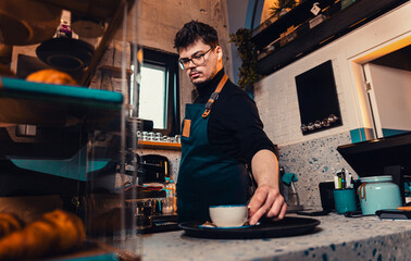 Barista working behind the counter in the cafe, getting ready to make coffee.