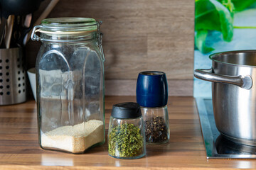 jar of spices sits on a wooden counter next to a pot