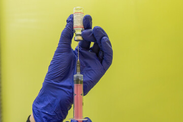 A nurse in blue gloves draws medicine into a syringe for an injection. Treatment in hospital. The...